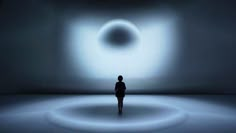 a person standing in the middle of a dark room with a light coming from it