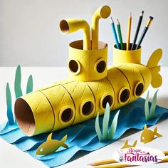 a yellow submarine made out of toilet paper next to pencils and markers on a white surface