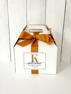 a white box with an orange ribbon tied around the front and side of it that says welcome