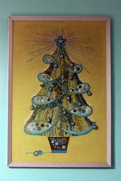 a painting of a christmas tree on a yellow background with blue trimmings and beads