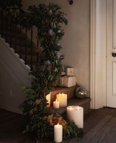 candles are lit on the floor next to a christmas tree