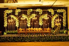 a stage set up with couches, flowers and greenery for a wedding reception