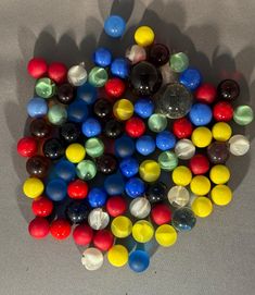 a pile of different colored marbles sitting on top of a white table next to each other