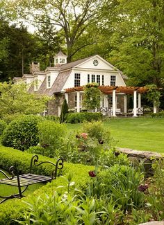 a bench in front of a house surrounded by greenery