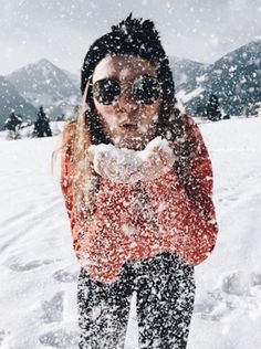 a woman standing in the snow wearing sunglasses