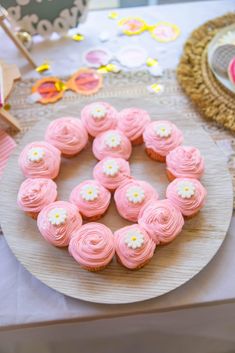 pink cupcakes are arranged in the shape of a wreath on a table with other decorations