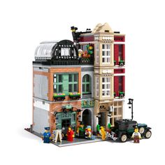 a lego model of a building with people standing in front of it and cars parked outside