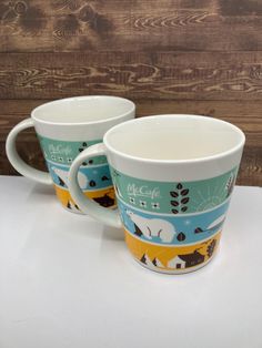 two coffee mugs sitting next to each other on a table