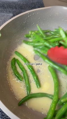 green beans and red pepper being cooked in a wok on the stove with oil