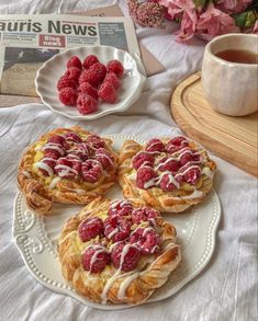 raspberry pastries on a white plate next to a cup of coffee