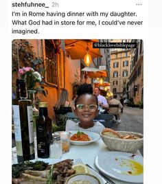 a woman sitting at a table with plates of food and wine in front of her