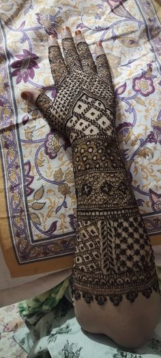 a woman's hand with henna on it sitting on top of a bed