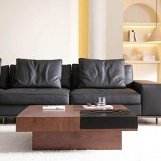 a living room with two black couches and a coffee table in front of it