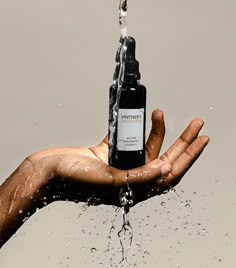 a person's hand holding a bottle of water in the air with splashing from it