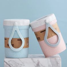 two cups with handles are sitting on a marble block