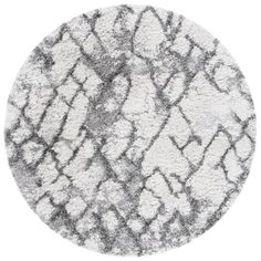 a round rug with grey and white designs on the top, in front of a white background