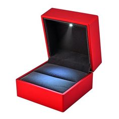 an open red box with a ring in it's center and light shining on the inside