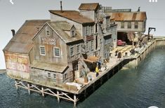 an old wooden building sitting on top of a body of water next to a pier