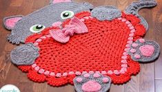 a crocheted rug with a cat holding a heart on it's back