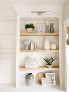 the shelves are filled with vases, books and pictures