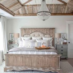 a bedroom with a bed, dresser and chandelier hanging from the wooden ceiling