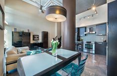 a dining room table with blue chairs in front of a kitchen and living room area