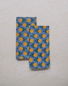 two blue and yellow napkins with oranges on them sitting next to each other