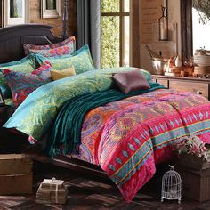 a bed with colorful comforters and pillows in a room