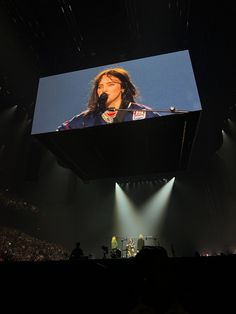 a person on a stage with a microphone in front of a large screen and lights