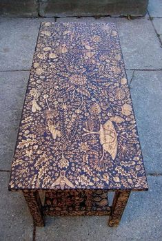 a wooden table with an intricate design on it's top sitting on the sidewalk