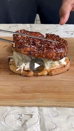 a person cutting into a sandwich on top of a wooden board