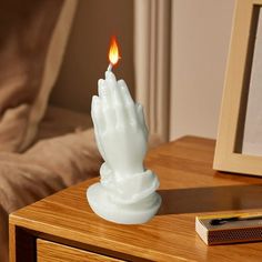 a small white candle sitting on top of a wooden table next to a framed photo