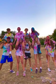 a group of young people standing next to each other on top of a dirt field