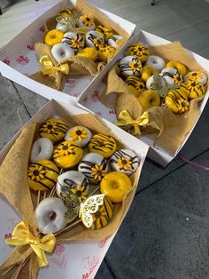 two boxes filled with yellow and white decorated donuts