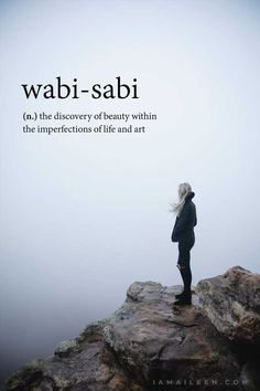 a woman standing on top of a cliff with her back to the camera and texting wabi - sabi