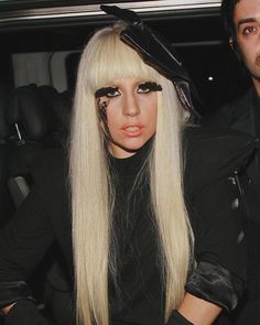 a woman with long white hair and black makeup is sitting next to a man in a car