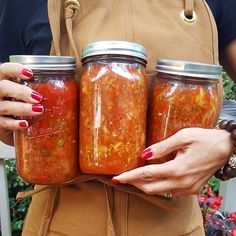 two women holding jars filled with food in front of their backs and one has her hands on the hips