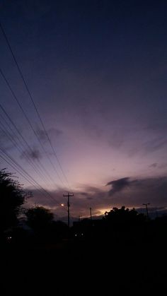 the sky is dark and purple with power lines in the foreground at night time