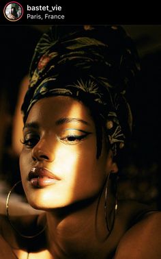 a woman with her eyes closed wearing large hoop earrings and a turban hat