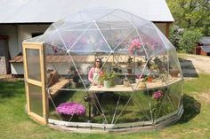 a woman sitting in a greenhouse with potted plants inside