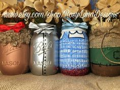 four mason jars with flowers in them are lined up on a tableclothed surface