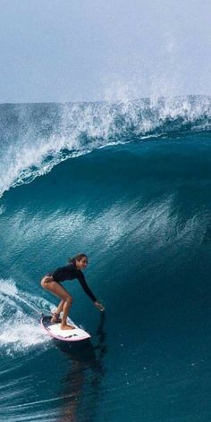 a woman riding a wave on top of a surfboard