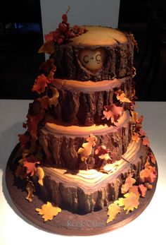 a three tiered cake decorated with leaves and an owl on it's face