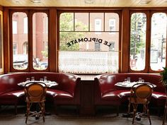 two booths with tables and chairs in front of large windows that look out onto the street