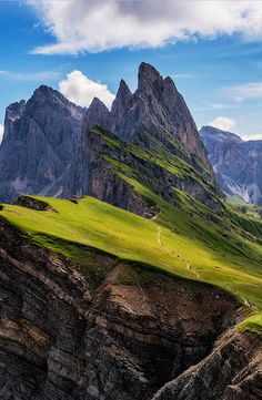 the mountains are covered in green grass and there is a trail going through them that goes up to the top