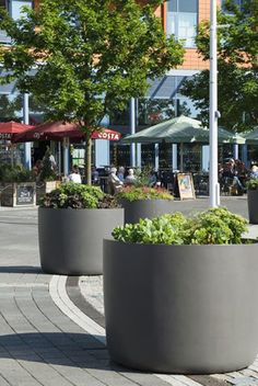 three large planters with plants in them on the sidewalk