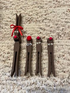 three brown wooden sticks with red noses and eyes are on the carpet next to each other