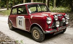 an old red car driving down a dirt road