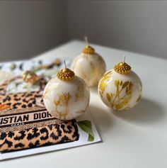 three white and gold ornaments sitting on top of a table next to a book with an animal print cover