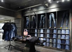 a clothing store with jeans hanging on the wall and clothes on display in front of them